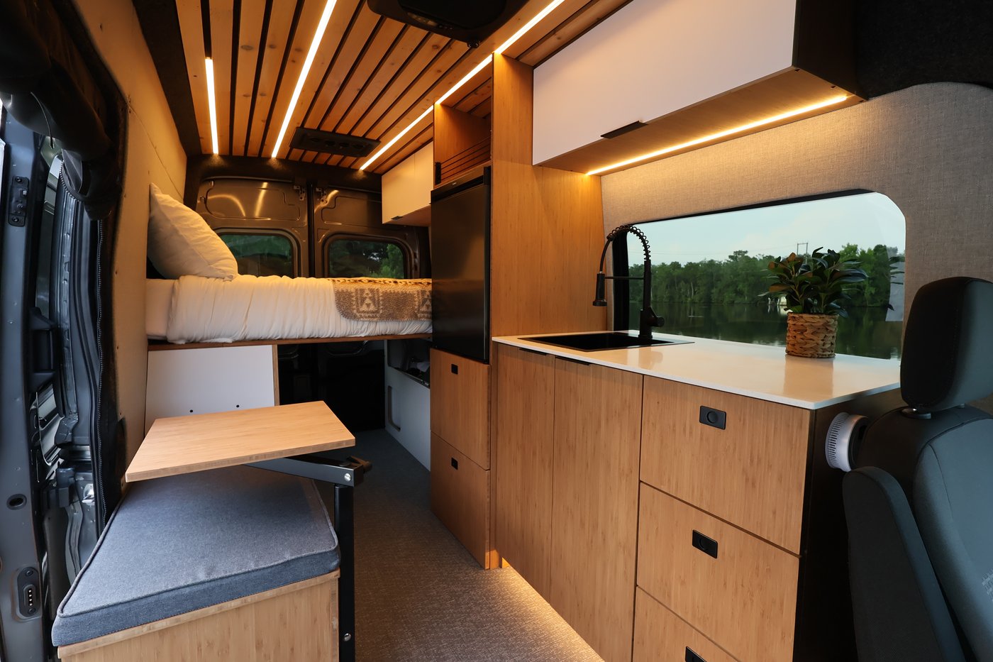 Aire camper van interior looking toward the rear, with bamboo cabinetry and cedar slatted ceiling