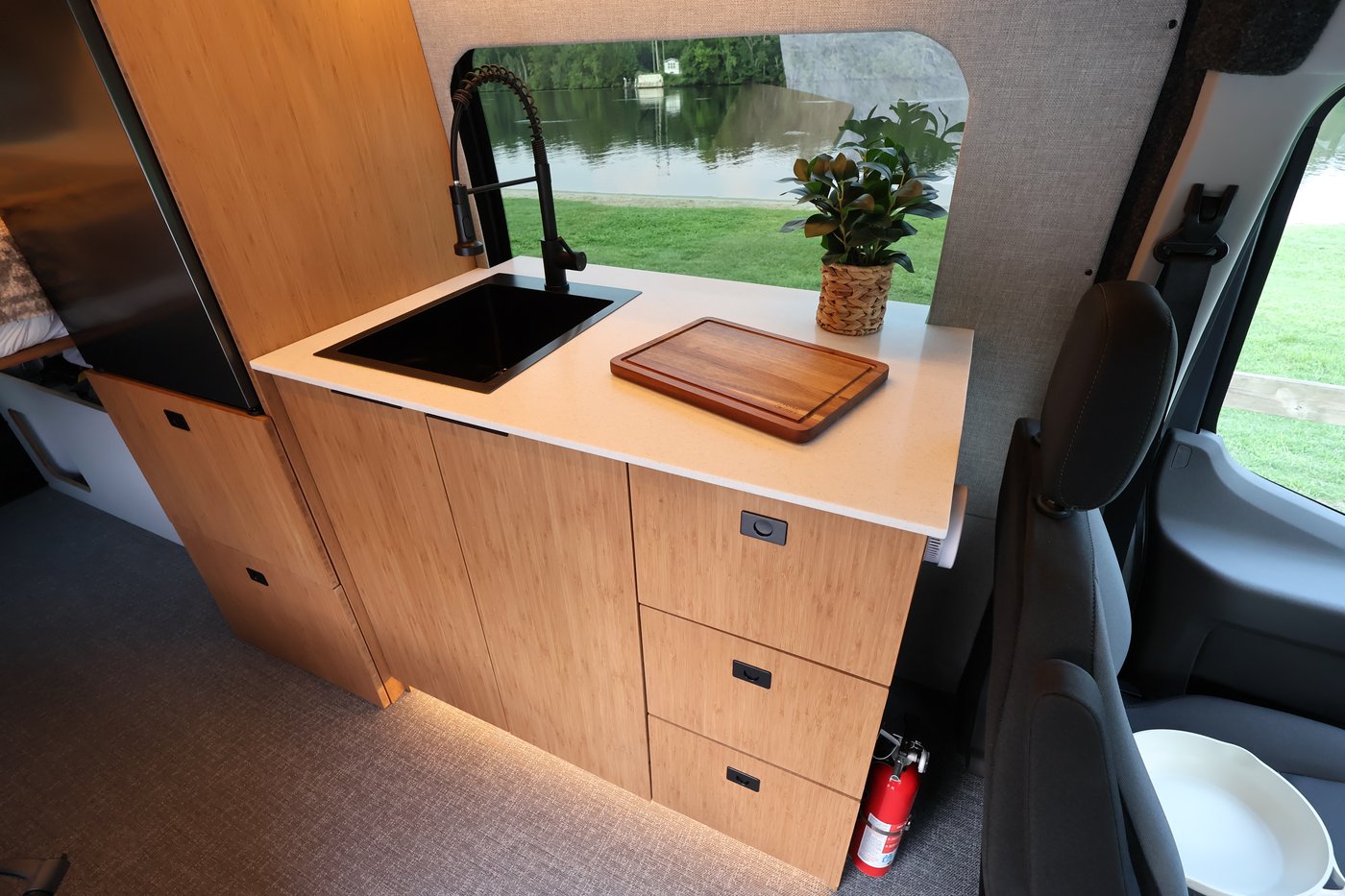 Aire galley kitchen with Corian countertop, cutting board, and potted plant