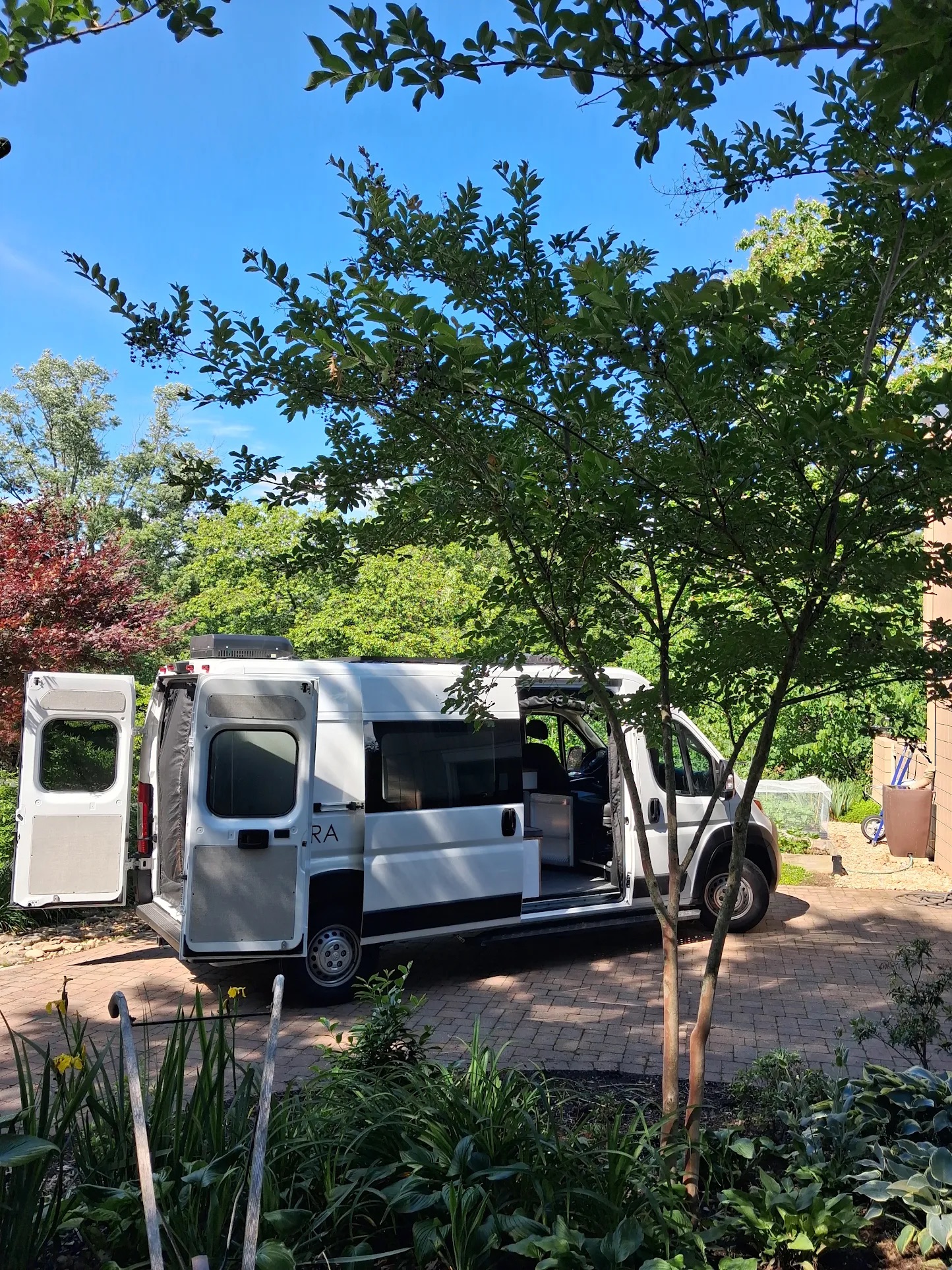 Vantra camper van owner beside their custom build with kayaks